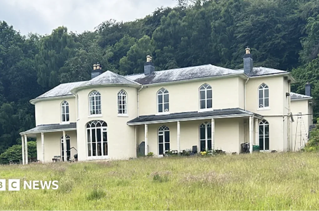 Residents walking beside a Georgian hall and its grounds in rural Powys