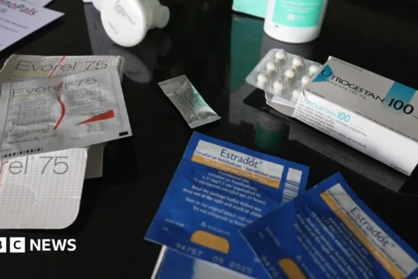 A woman holds a hormone prescription bottle while discussing menopause treatment